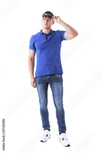 Adult man in casual clothes holding sunglasses and looking up interested. Full body isolated on white background. 