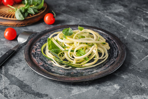 Plate with zucchini spaghetti on grey table