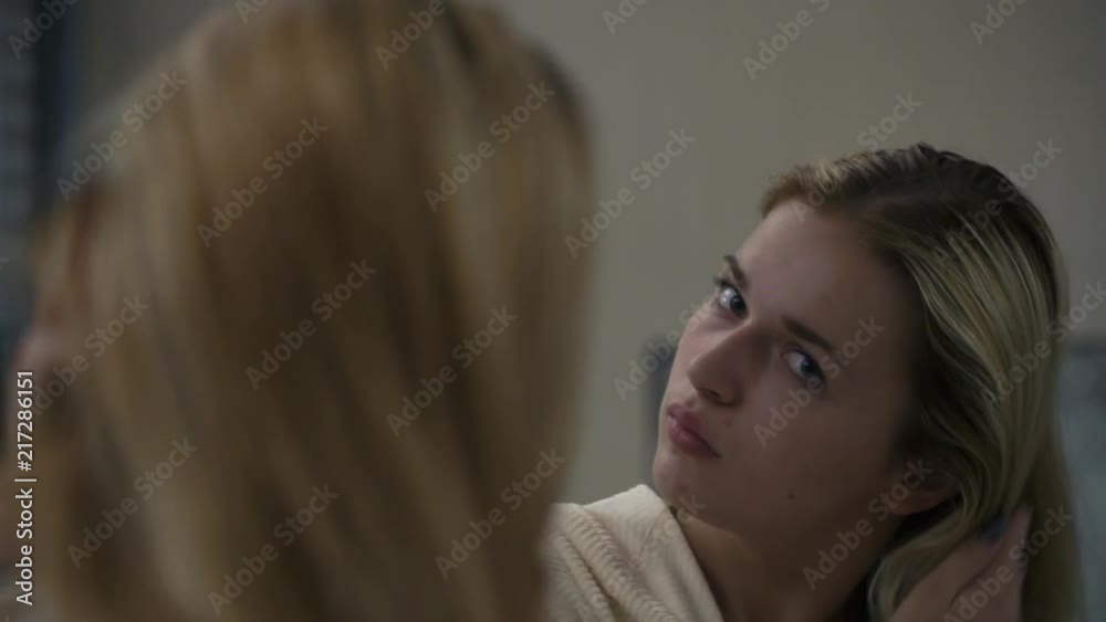 Beautiful girl combs her hair in front of a mirror