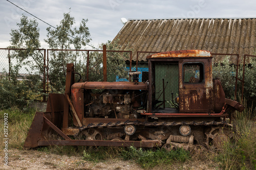 Old rusty broken rural tractor stands in the backyard