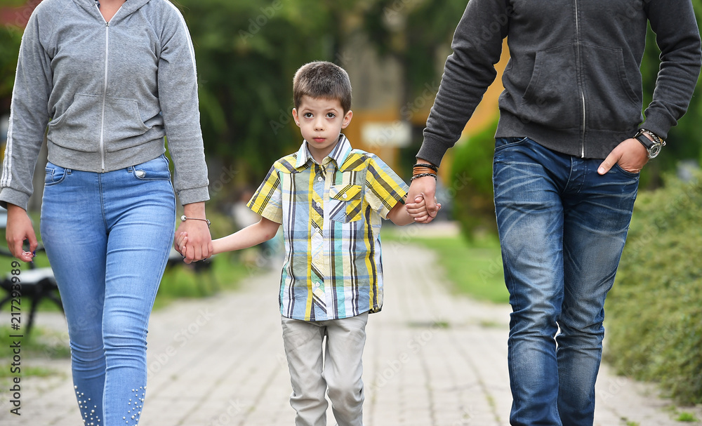 mother, father and son holding hands in park mother, father and son holding hands in park