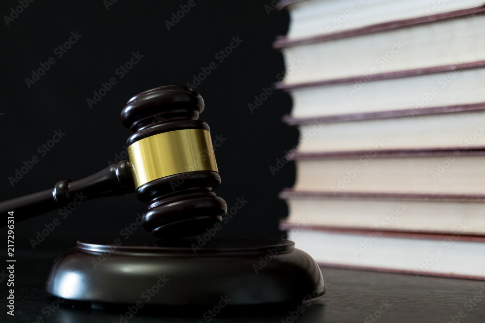 Judge gavel beside pile of books on wooden background Judge gavel beside pile of books on wooden background