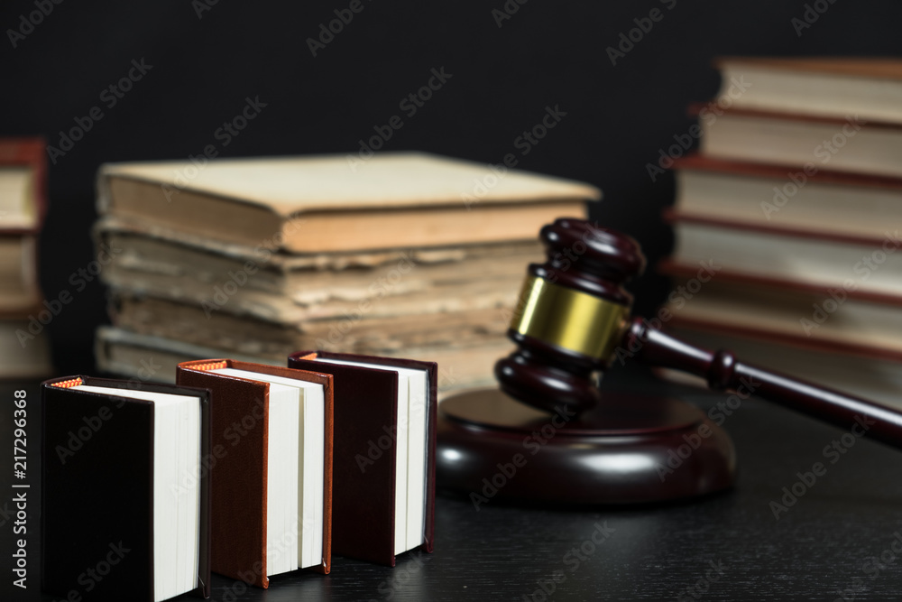 Judge gavel beside pile of books on wooden background Judge gavel beside pile of books on wooden background