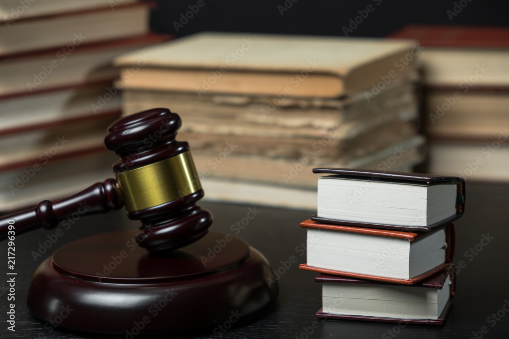 Judge gavel beside pile of books on wooden background Judge gavel beside pile of books on wooden background