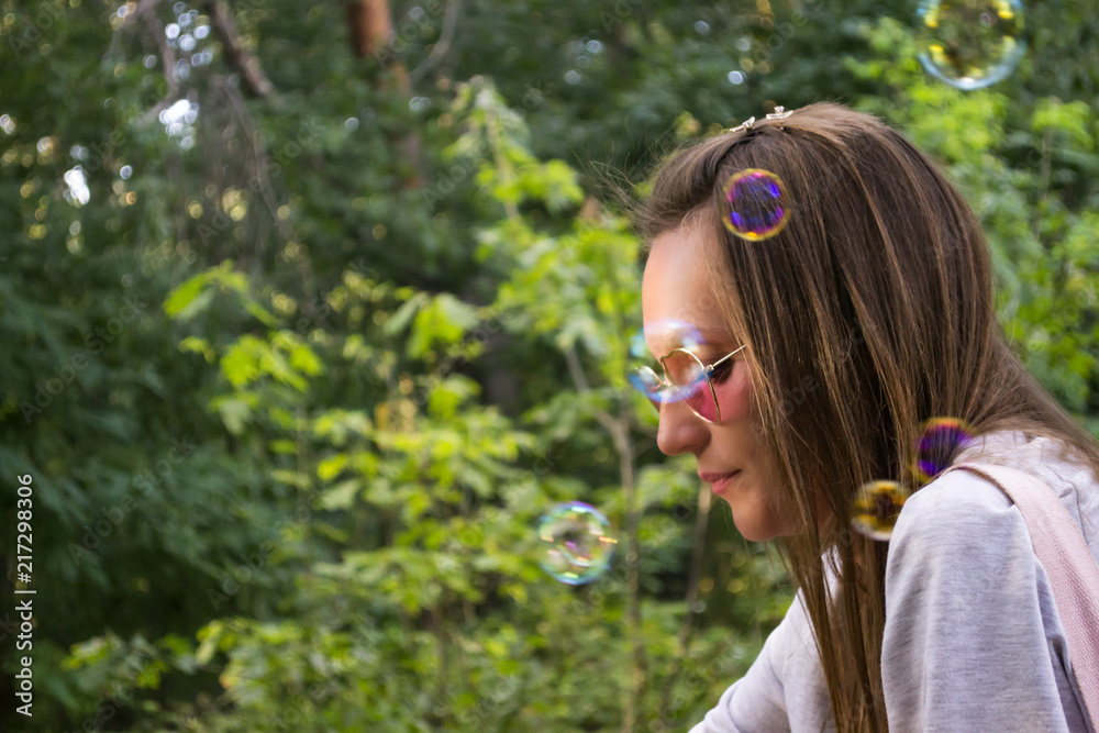 Girl blowing a soap bubbles outdoor. Happy summer holidays.