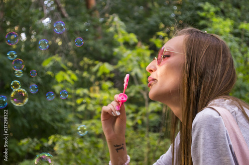 Girl blowing a soap bubbles outdoor. Happy summer holidays.