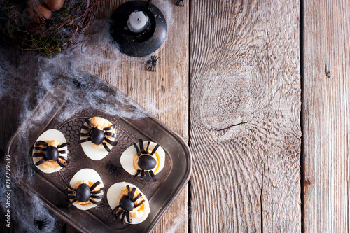 The idea for decorating a table for Halloween: stuffed eggs with spiders of olives, top view, copy space