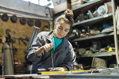 young woman fixing tool at work