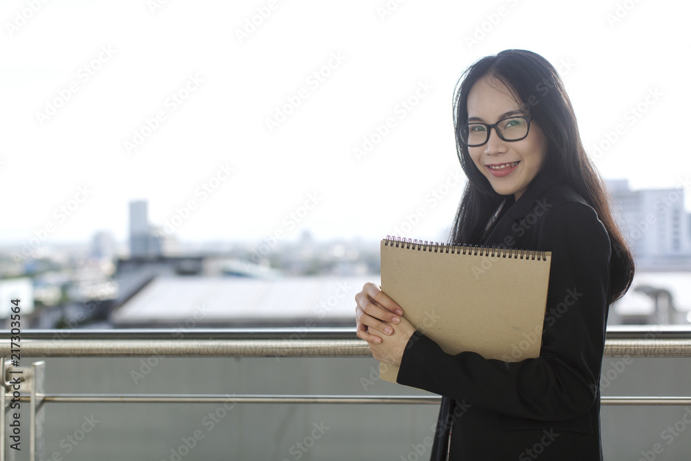 Young Asian business woman wear suit holding file document, standing at office Young Asian business woman wear suit holding file document, standing at office