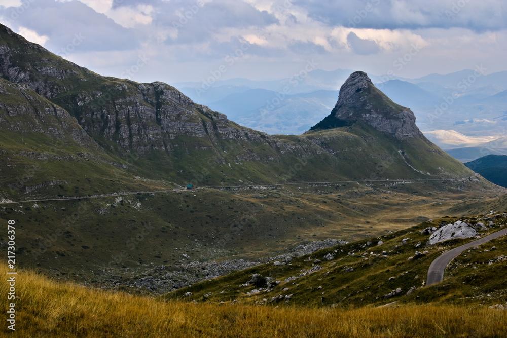 A mountain road leading through rocky meadows and hills