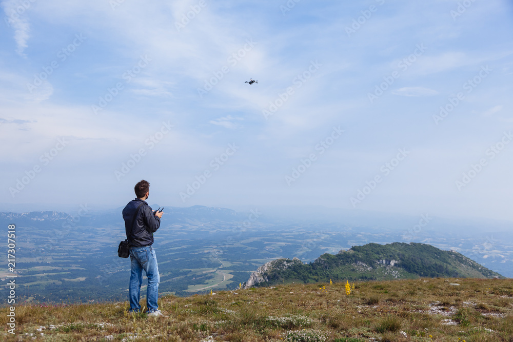 Young man flying drone over mountain