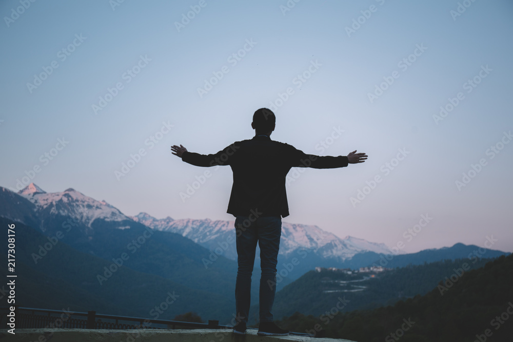 a young man admires the mountain scenery, spread his hands to meet nature