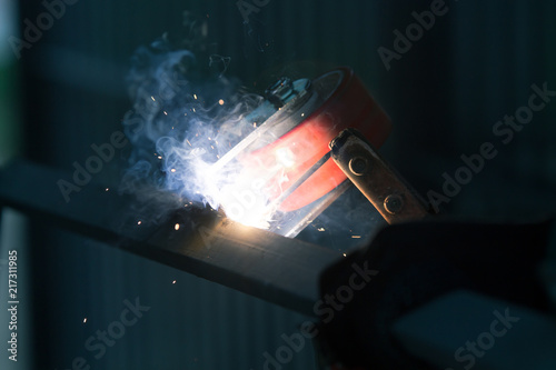 welder is welding metal part with lots of sparks