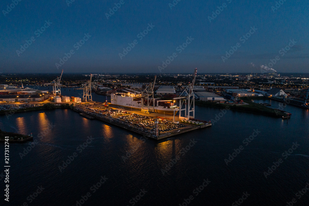 Aerial view of big cargo ship loading with containers at port of Hamburg, Germany. Beautiful sunset.