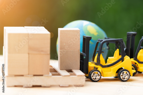 Mini forklift trucks load stack of cardboard boxes on wooden pallet with nature background and globe. Logistics and transportation management ideas and Industry business commercial concept.