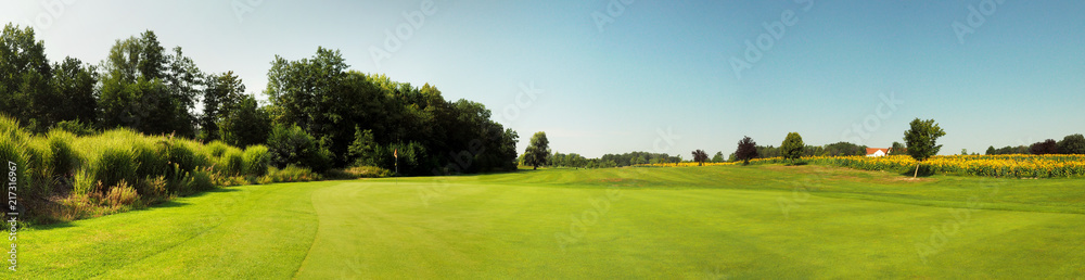 Grüne Golfplatz Wiese am Sonnenblumenfeld - Panorama im Sommer Grüne Golfplatz Wiese am Sonnenblumenfeld - Panorama im Sommer