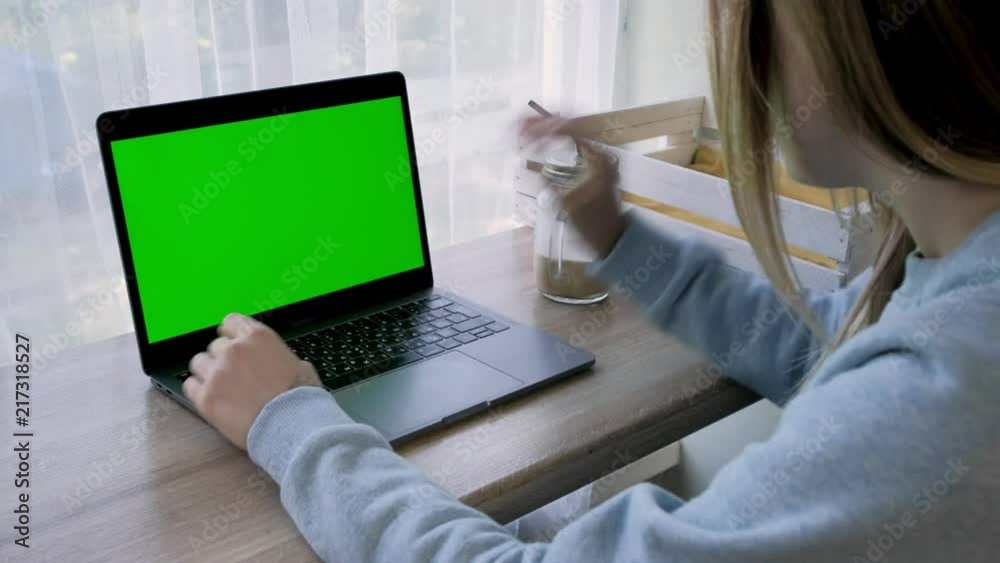 Girl using laptop with green screen and drinking coffee/close-up. Girl using laptop with green screen and drinking coffee/close-up.