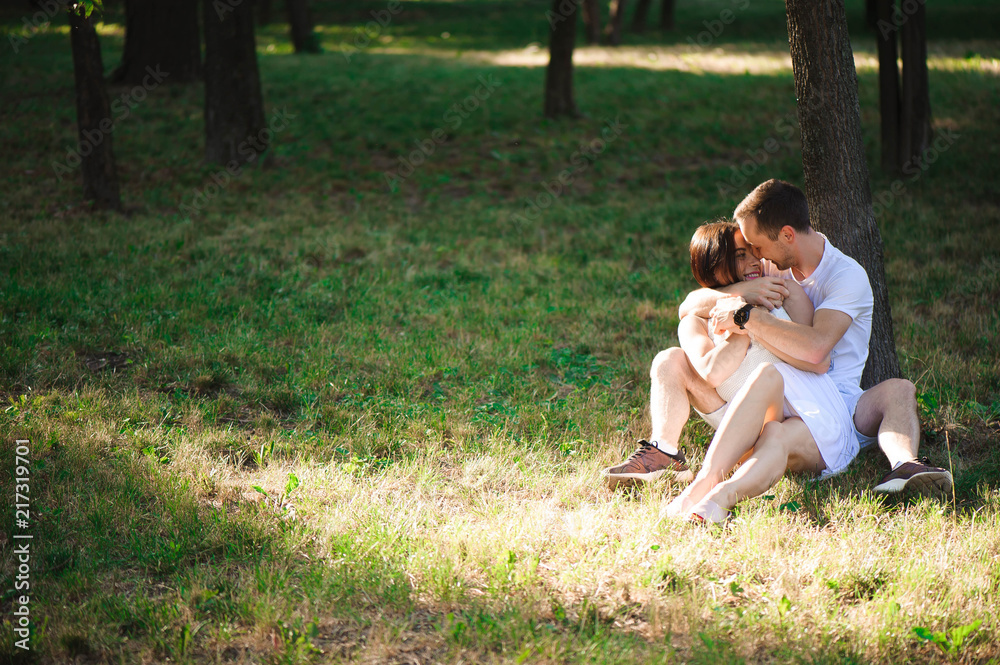 A beautiful couple is resting outside the city, sitting near a big tree in the garden. Love story A beautiful couple is resting outside the city, sitting near a big tree in the garden. Love story