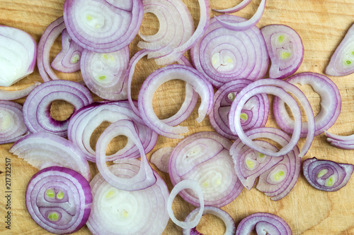 Sliced red onion rings on wooden background top view