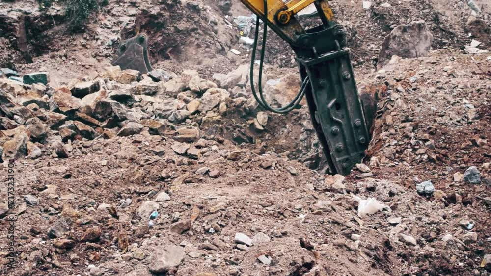 Close up of a heavy duty construction industry excavator machine crushing stones in a construction site Close up of a heavy duty construction industry excavator machine crushing stones in a construction site