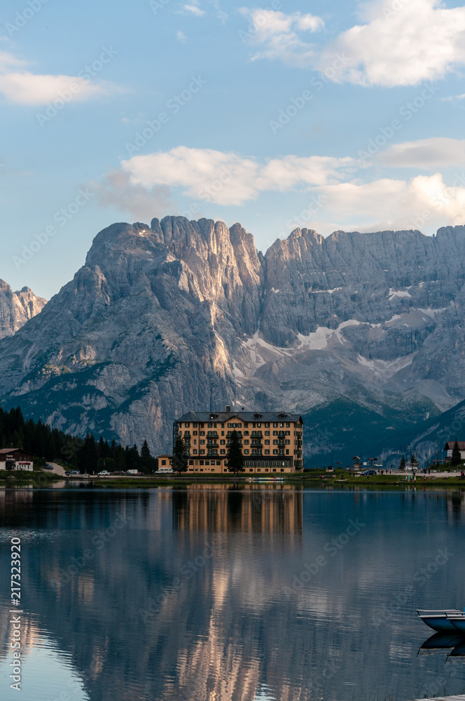 Fototapeta premium Buildings along the shoreline are reflected in the calm waters of Lake Misurina in the Italian Dolomites, just before sunset.