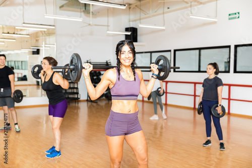 Sporty Woman Carrying Barbell On Shoulders In Gym