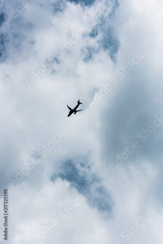 low angle view of airplane flying in blue cloudy sky