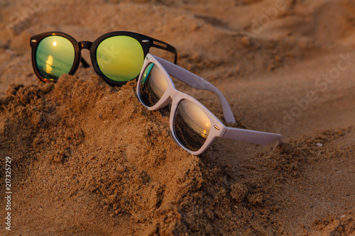 Sunglasses lying on the sandy beach on the sunset.