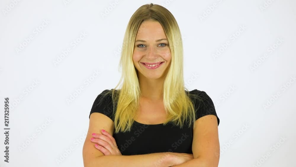 A young beautiful woman folds her arms across her chest and smiles at the camera - white screen studio