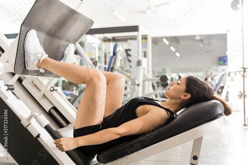 Woman Exercising And Flexing Leg Muscles On Gym Machine