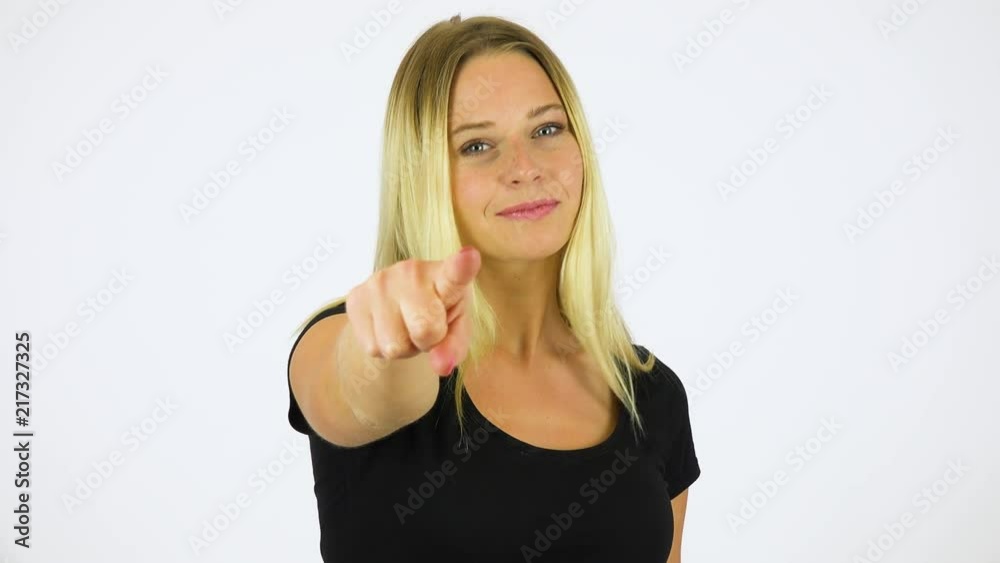 A young beautiful woman points at the camera with a smile - white screen studio A young beautiful woman points at the camera with a smile - white screen studio