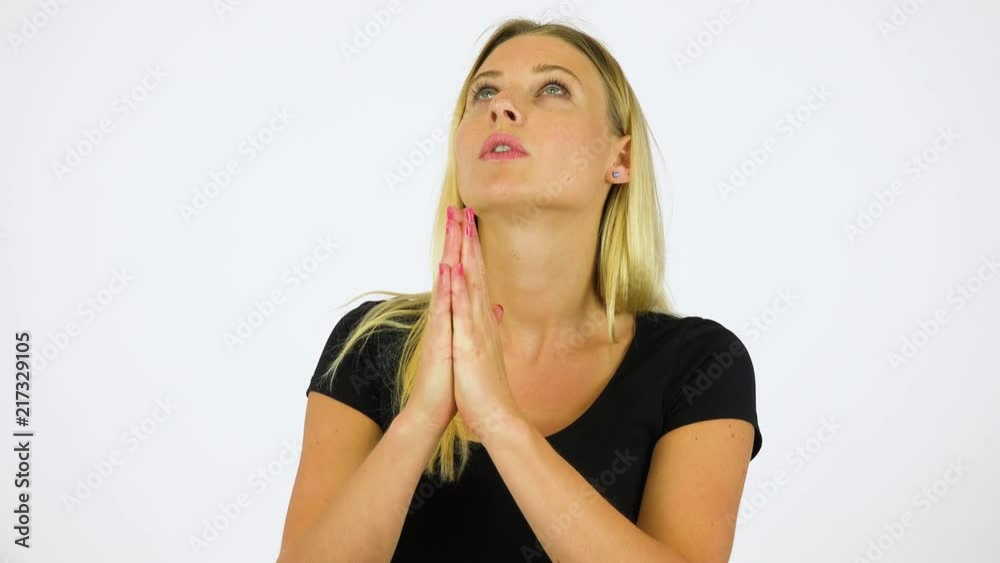 A young beautiful woman prays with her hands clasped together - white screen studio A young beautiful woman prays with her hands clasped together - white screen studio
