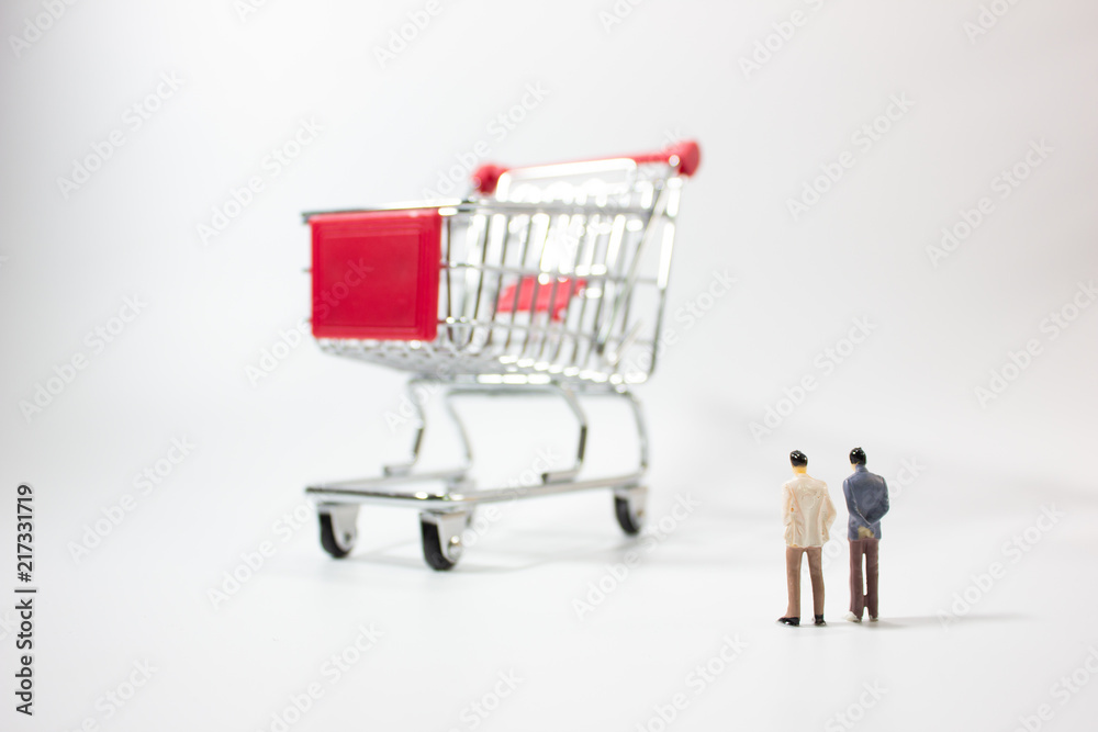 Two miniature businessman looking shopping cart isolated white background. Two miniature businessman looking shopping cart isolated white background.