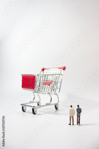 Two miniature businessman looking shopping cart isolated white background.