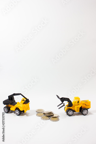 Miniature excavator truck and forklift working with coins isolated white background vertical.