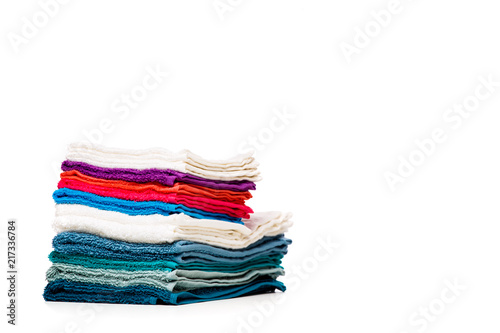 Photo of stacks multi-colored towels on empty white background.