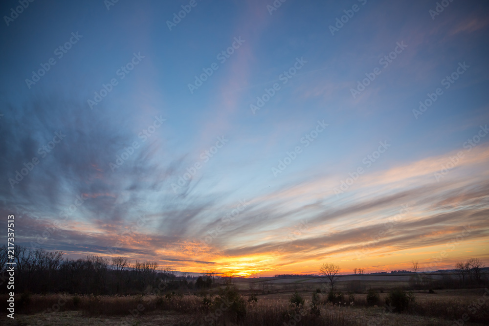 Obraz premium Partially Cloudy Dramatic Sunset Sky over Winter Fields and Meadows.