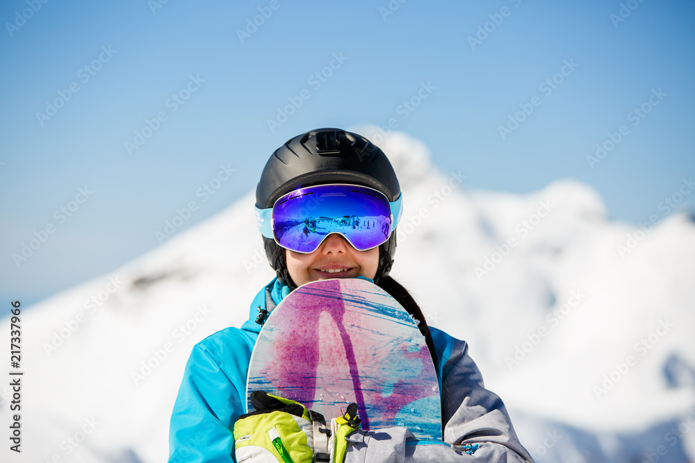 Photo of young woman tourist in helmet looking into camera with snowboard in hands Photo of young woman tourist in helmet looking into camera with snowboard in hands