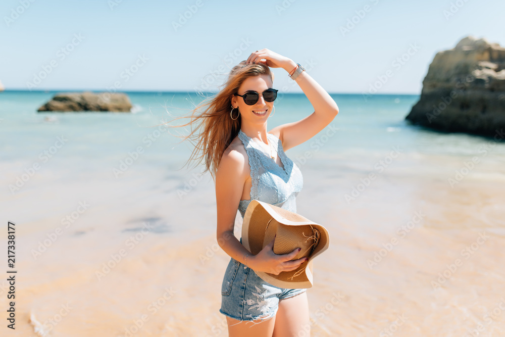 Young woman in straw hat walking on sea beach Young woman in straw hat walking on sea beach