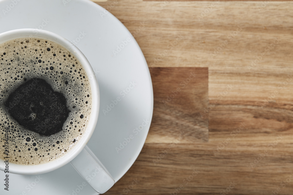 Obraz premium Cup of coffee on wooden table with copy space. Top view.