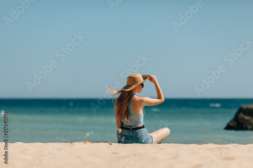 Wallpaper Mural Rear view of woman in straw hat relaxing on sandy beach view on ocean Torontodigital.ca