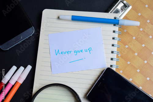 Never Give up word written on paper. Never Give up text on workbook, technology business concept photo