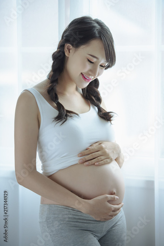 Free Download Young Pregnant Asian Woman Holds Her Hands on Her Swollen Belly, Love Concept. - GFXLoad