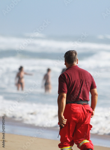 Valokuva A rescuer walking on the beach with a transceiver in the hand