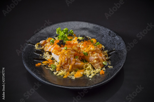 Aburi Spicy Salmon Nigiri, Burned Salmon Sushi and topped with Shrimp Eggs, tempura and spicy sauce served on traditional Japanese food on ceramic dish, Japanese food style, selective focus