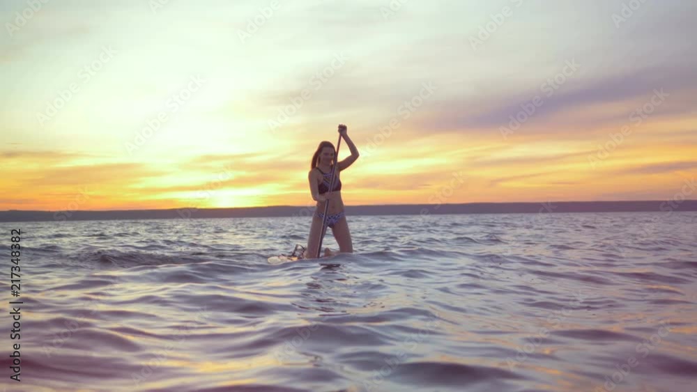 Happy woman floats on a surfboard. Professional surfer rides a board in the evening. Happy woman floats on a surfboard. Professional surfer rides a board in the evening.