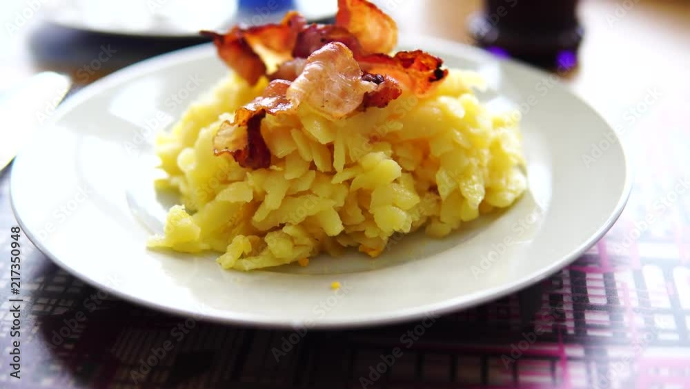 putting bacon on potato rosti. typical swiss breakfast mea putting bacon on potato rosti. typical swiss breakfast mea