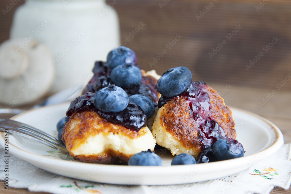 Homemade cheese donuts with berry jam and blueberry. Healthy breakfast or snack, round plate, rustic wooden background. Homemade cheese donuts with berry jam and blueberry. Healthy breakfast or snack, round plate, rustic wooden background.