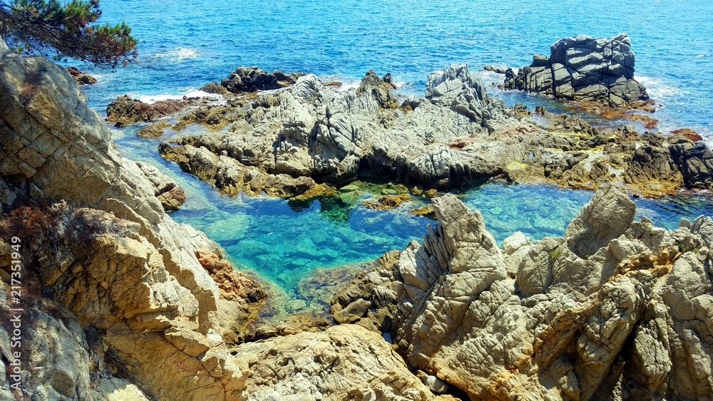 Rocks in blue sea. View on rocks in the Balearic sea. Postcard view on cliffs in the Balearic sea. Lloret de Mar sea view.