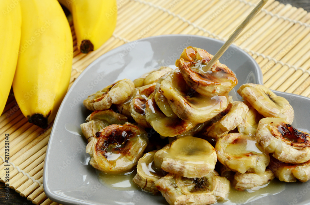 Grilled Bananas With Coconut- Caramel Sauce with fresh bananas on bamboo mat. Grilled Bananas With Coconut- Caramel Sauce with fresh bananas on bamboo mat.